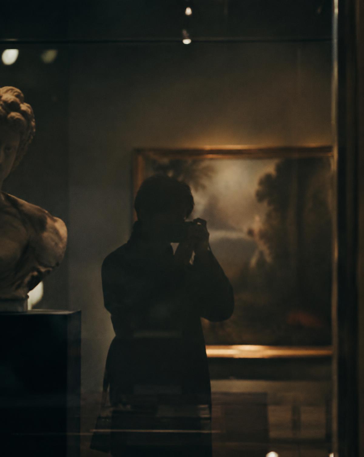 A photographer's silhouette reflected in museum glass